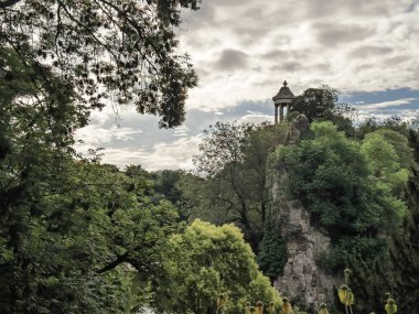 Paris 'teki Parc des Buttes Chaumont' ta Ile du Belvedere, Sybille Tapınağı ile birlikte yoğun yeşilliğin üzerindeki kayalık bir uçuruma tünemiş, parkın dramatik romantik bahçe tasarımını gösteriyor..