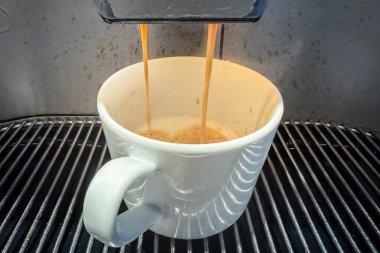 Fasulyeden fincana kadar espresso dolu beyaz bir fincanı yakından görmek, köpüklü kremanın üzerine köpüklü krema dökmek, bir kafede ya da mutfakta otomatik kahve hazırlamak..