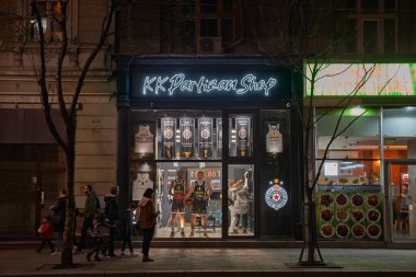 BELGRAD, SERBIA - 30 Aralık 2023: Club logosu ve formalarıyla Belgrad 'daki KK Partizan mağazasının gece görüşü. Kosarkaski Klub Partizan Sırbistan 'ın en büyük basketbol kulüplerinden biri.