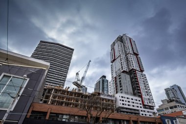 Toronto, Kanada 'nın merkezindeki Queen Caddesi' nde inşaat faaliyetleri, mevcut kulelerin yanında yükselen yeni apartman kuleleri etrafındaki vinç ve iskeleler, kentsel kalkınma ve konut büyümesini yansıtıyor.