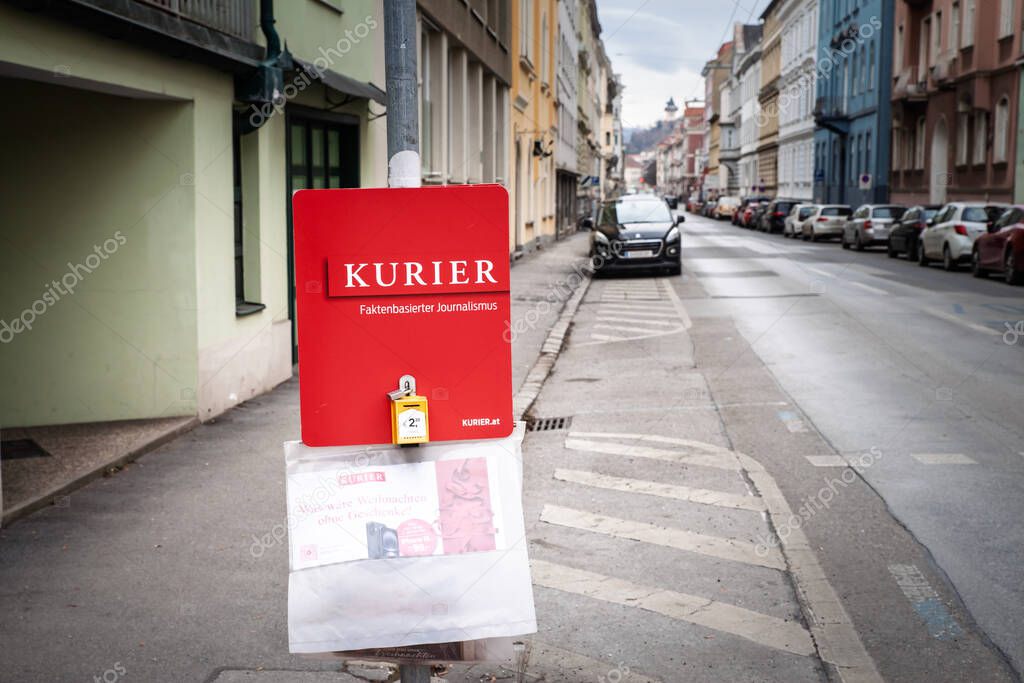 GRAZ, AUSTRIA - DECEMBER 22, 2024: Red street sign promoting the Austrian daily Kurier on a city sidewalk in Graz. Part of Funke Mediengrupper, Kurier Tageszeitung is an austrian newspaper.