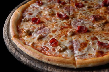 Pizza, et, sosis ve siyah bir arka plan 4 et tavuk ile ahşap bir gemide