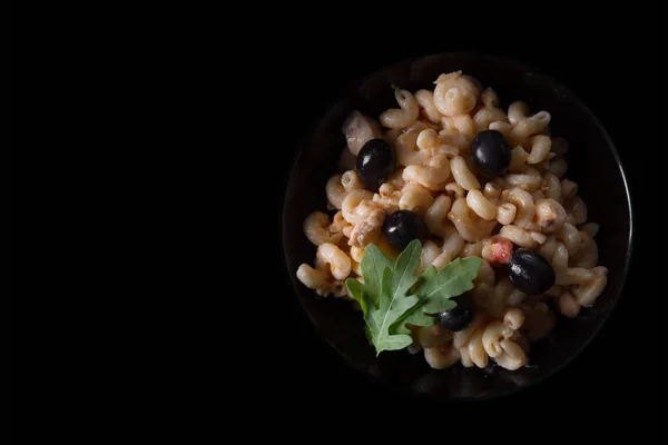 Macaroni with meat and olives on a black background — Stock Photo, Image