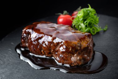 Siyah bir taş üzerinde teriyaki soslu domuz eti biftek