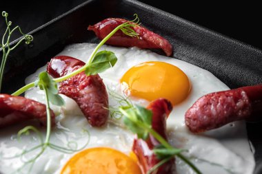 Leziz kahvaltı, sosis ve Genç bezelye çekimleri, üzerinde siyah bir tavada kızarmış yumurta