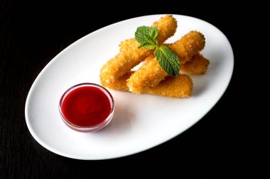 Peynir nuggets soslu, siyah bir arka plan üzerinde beyaz bir plaka üzerinde