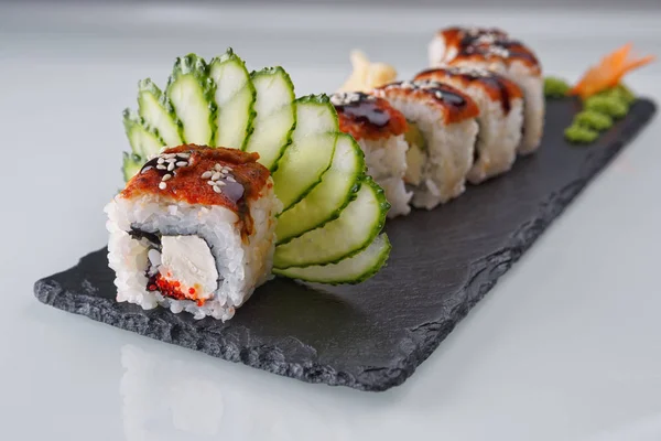 Sushi Roll dragon, on black stone, on white background, close up