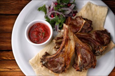 Sos ve soğan ile beyaz bir plaka üzerinde kızarmış kaburga. ahşap bir gemide