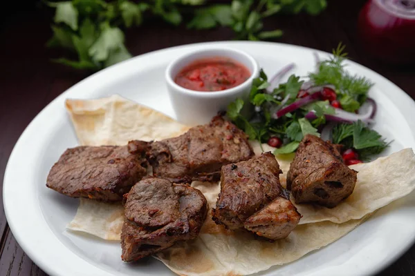 Beyaz bir plaka üzerinde şiş kebap