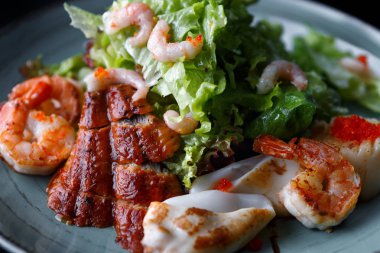 Deniz ürünleri salatası. Karides, el balığı, kalamar, marul. Karanlık bir bac karşı