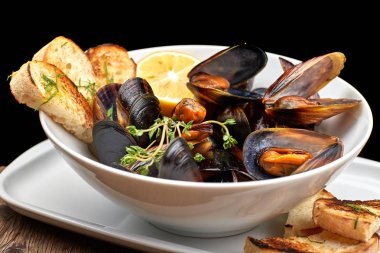 Ahşap bir tahta üzerinde beyaz bir tabak üzerinde Midye