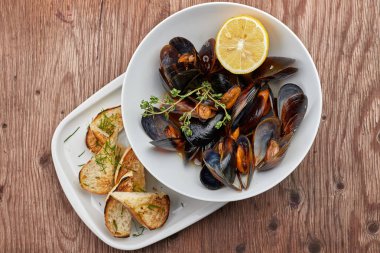 Ahşap bir tahta üzerinde beyaz bir tabak üzerinde Midye