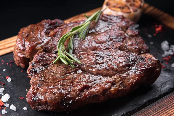 Smažený masový steak na břidlici na černém pozadí — Stock fotografie