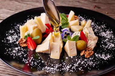 Bal dökülen siyah bir tabak üzerinde peynir tabağı