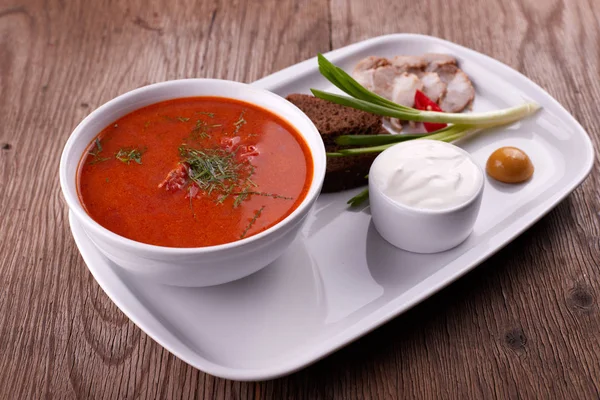 Ukrainischer Borschtsch mit saurer Sahne, Zwiebeln und Speck auf weißem — Stockfoto