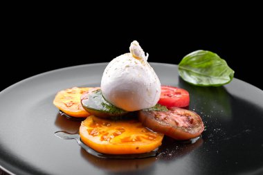 Pesto sos ve siyah bir plat üzerinde domates ile Buratta mozzarella