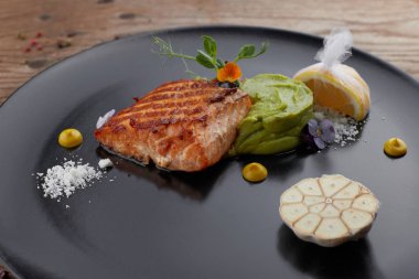 Limonlu siyah bir tabakta kızarmış somon parçası. Biftek. F