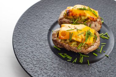 Peynir ve herbares ile Fırında patates, siyah bir tabakta