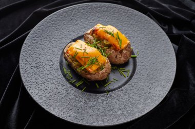 Peynir ve herbares ile Fırında patates, siyah bir tabakta