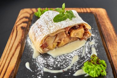 Koyu bir arka plan üzerinde ahşap bir tahta üzerinde Elma strudel