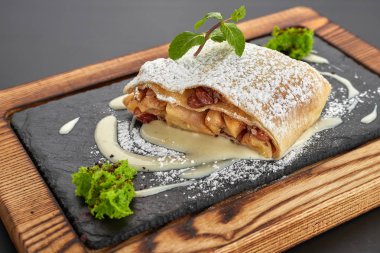 Koyu bir arka plan üzerinde ahşap bir tahta üzerinde Elma strudel
