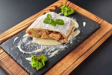 Koyu bir arka plan üzerinde ahşap bir tahta üzerinde Elma strudel