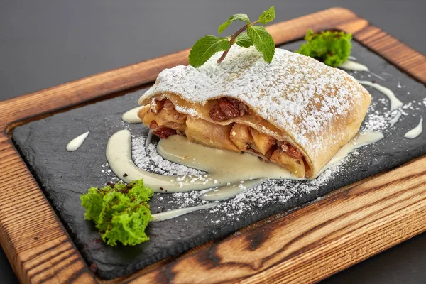 Apple strudel on a wooden board on a dark background — Stock Photo, Image