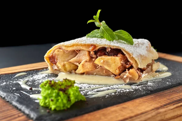 Manzana strudel sobre una tabla de madera sobre un fondo oscuro —  Fotos de Stock