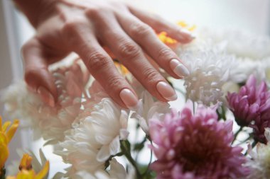 Çiçeklerin arka planına karşı güzel kadın elleri. Frenc