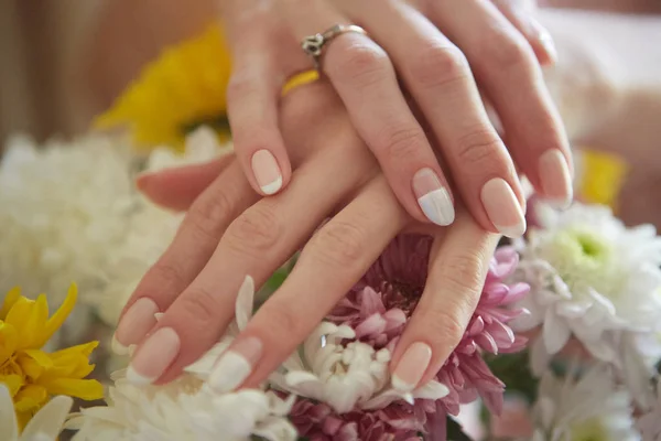 Mãos de mulheres bonitas contra o fundo das flores. Francês. — Fotografia de Stock