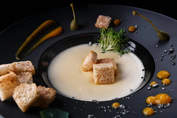 Грибной сливочный суп на черной тарелке — стоковое фото