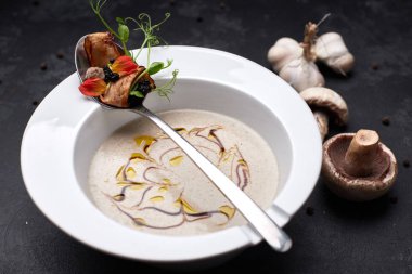 Siyah bir arka plan üzerinde beyaz bir tabak içinde mantar kremalı çorba