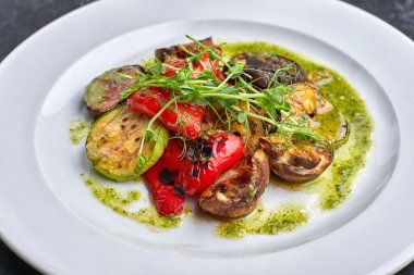 Izgara fırında sebze, patlıcan, kabak, dolmalık biber, şampiyon mantarı, siyah bir arka planda, mikro yeşil bir tabakta.