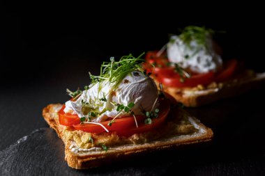 Siyah taş ve ahşap tahtada havyarlı, domatesli ve haşlanmış yumurta.