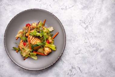 Izgara kalamar, mısır, havuç, domates ve marullu deniz ürünleri salatası.