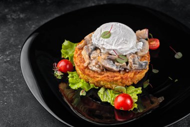 Mantarlı kızarmış biftek, siyah tabakta haşlanmış yumurta ve domates.