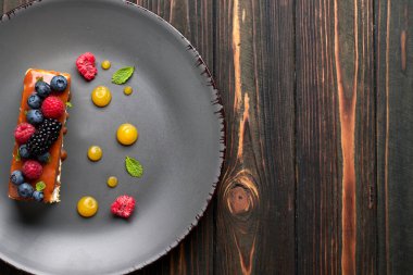 Bir dilim turta, ballı kek taze böğürtlen, nane ve karamel, ahşap arka planda.