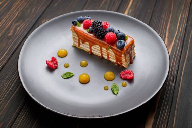 Bir dilim turta, ballı kek taze böğürtlen, nane ve karamel, ahşap arka planda.