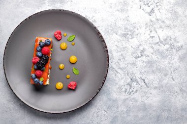 Bir dilim turta, arkaplanda taze böğürtlen, nane ve karamel ile ballı pasta.