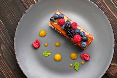 Bir dilim turta, ballı kek taze böğürtlen, nane ve karamel, ahşap arka planda.