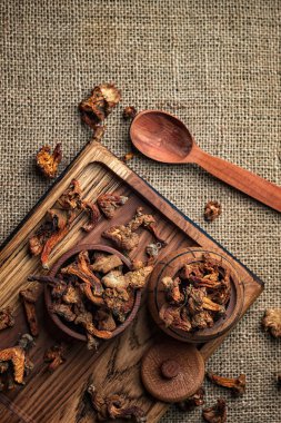 Kurutulmuş chanterelle mantarı, Cantharllus cibrius, ahşap bir tahtanın üzerinde, kabataslak bir arka planda, çuval bezi.