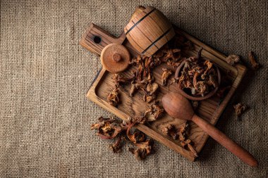 Kurutulmuş chanterelle mantarı, Cantharllus cibrius, ahşap bir tahtanın üzerinde, kabataslak bir arka planda, çuval bezi.