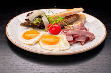 Domatesli sahanda yumurta, jambonlu ciabatta tostu, koyu arkaplanda. Kahvaltı.