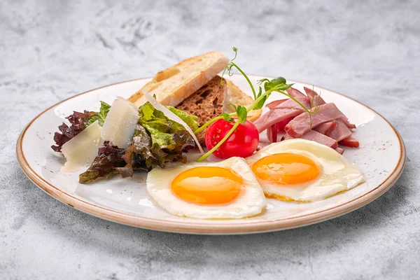 Kızarmış yumurta, domatesli, jambonlu ve ciabatta tostlu, beyaz arka planda. Kahvaltı.