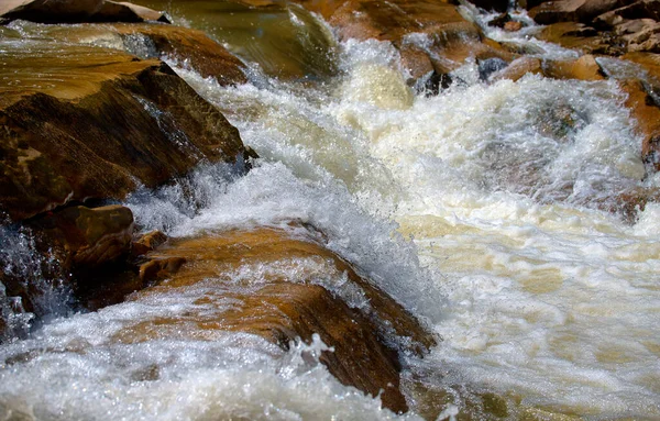 Rapids of a mountain river, stones, a seething river, on a sunny day, close-up