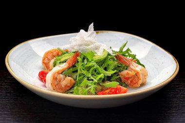 Karidesli salata, domates ve roka, beyaz bir tabakta, siyah bir arka planda