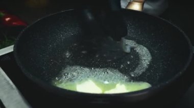 Adam çırpılmış yumurtayı tavada karidesle hazırlıyor. Yakın çekim videosu