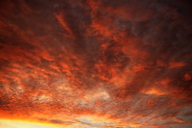 Parlayan kızıl gökyüzü ve ufukta dramatik sabah atmosferiyle canlı kırmızı gün doğumu