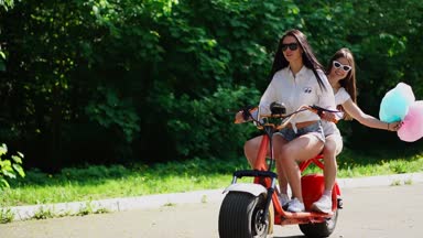 İki genç ve seksi kundaklama esmer bağsız kıl ile kısa denim şort ve beyaz gömlek bir elektrikli motosiklet parkta birbirlerine sarılma zevk devam