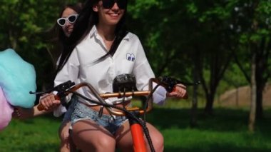 İki genç ve seksi kundaklama esmer bağsız kıl ile kısa denim şort ve beyaz gömlek bir elektrikli motosiklet parkta birbirlerine sarılma zevk devam